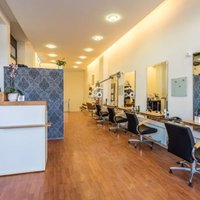 Innenansicht des Friseursalons mit vielen Stühlen, Spiegeln und einer Theke