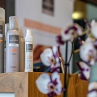 drei Produkte von Newsha hinter einer Orchidee